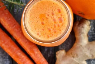 Suco detox de cenoura, laranja, pepino e gengibre servido em copo alto com gelo.